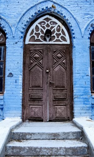 Entrance door in an old abandoned house with lock on it, blue facade in Moldova